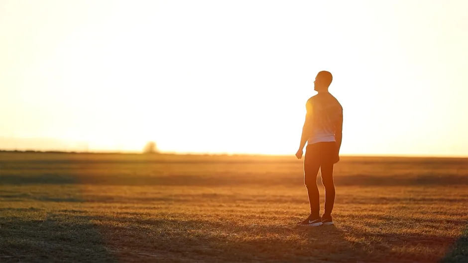 A person praying alone in an open field — anxiety surrendered to a caring God