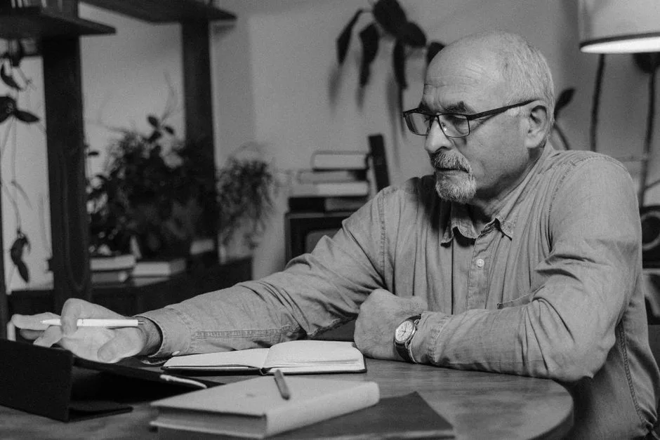 A man writing in a journal at a table, working through a workbook