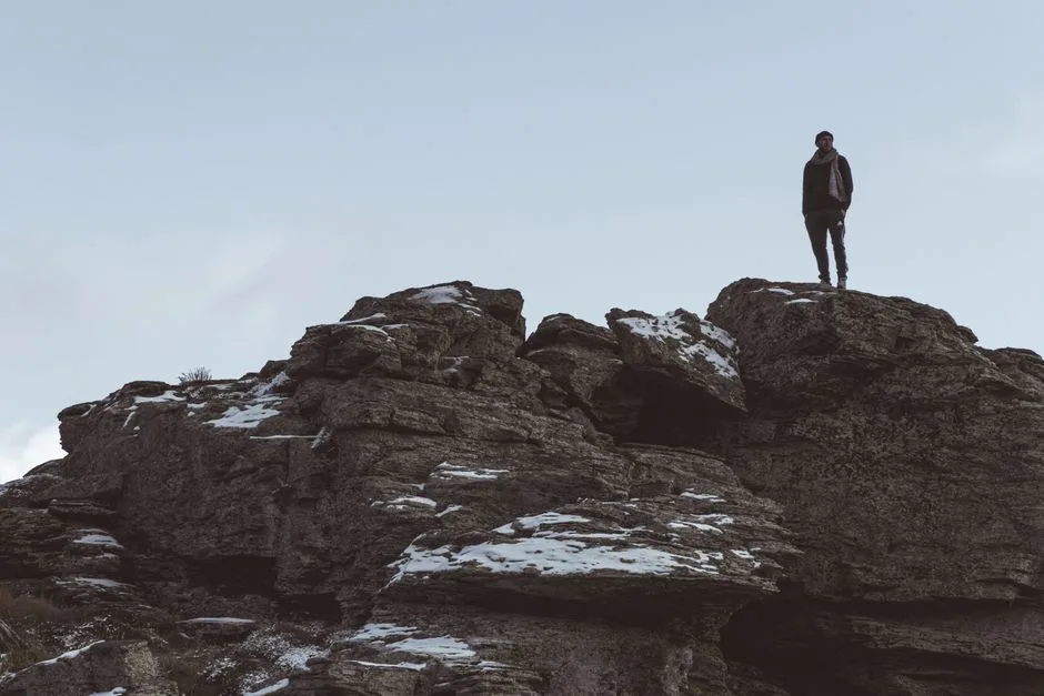 A man standing on a mountain summit, strength and courage rooted in God's presence