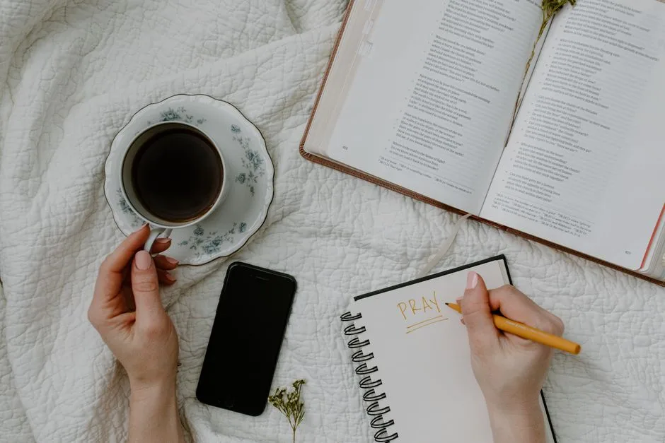 A woman sitting at a kitchen table in early morning with a Bible and a cup of coffee, starting her day in the Word before the house wakes up
