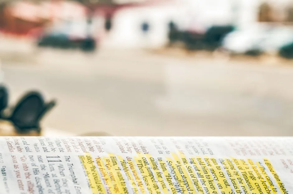 A person reading the Bible with a highlighter, working to understand a passage