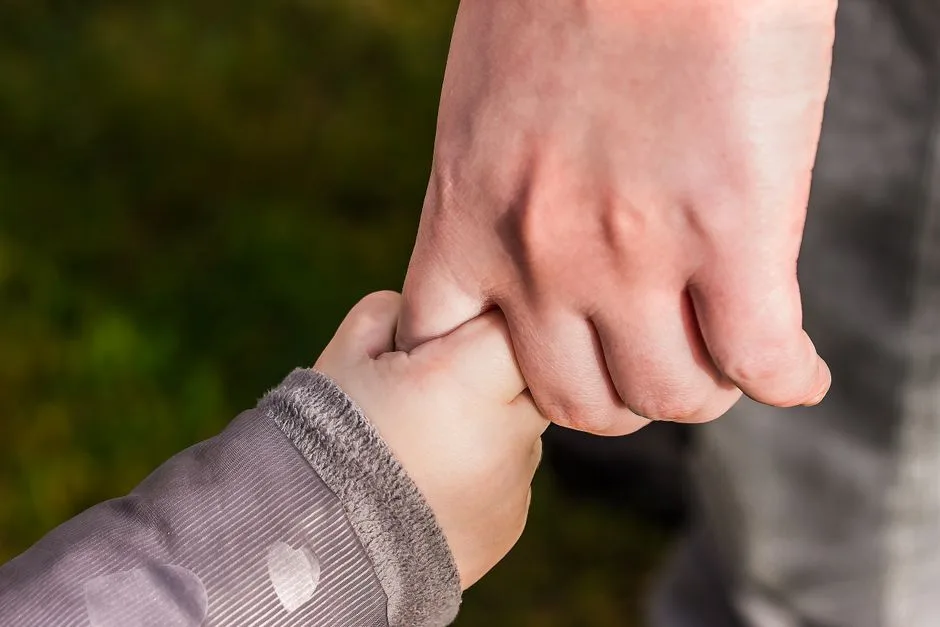 A mother's hands holding her child's hands — the foundation of honor across generations