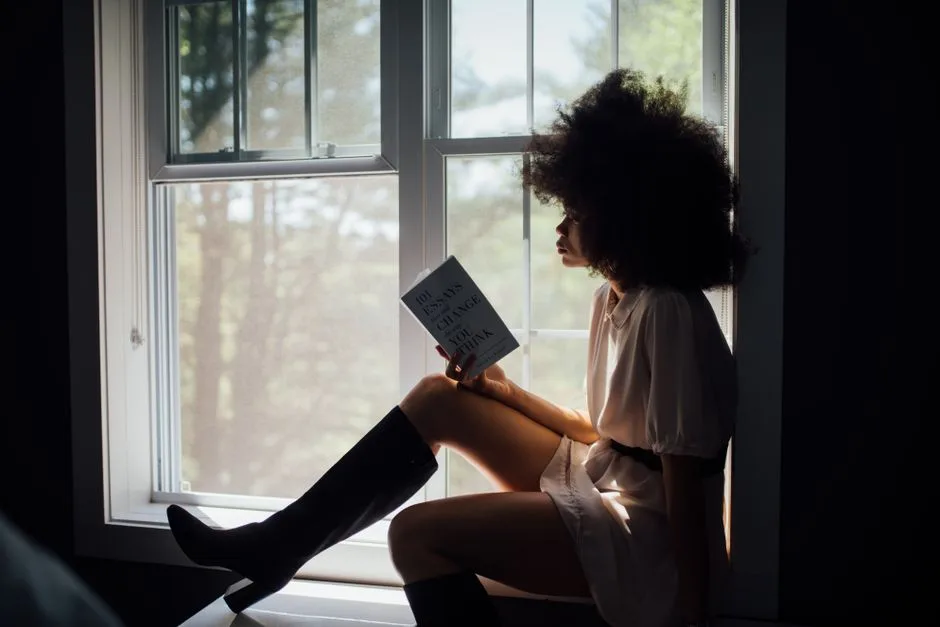 A woman reading quietly in soft natural light — beauty rooted in character rather than appearance
