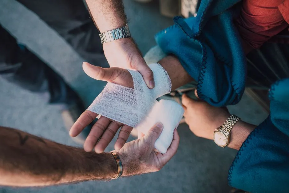 Hands gently bandaging a wound — the slow, real process of healing after harm