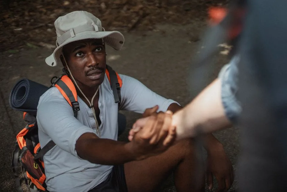 A leader kneeling to help someone up — authority modeled through service rather than domination