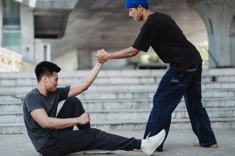 Strong hands gently helping someone up — strength expressed through service rather than domination