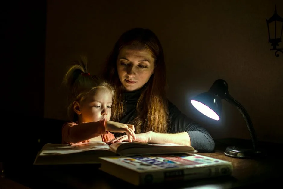 A parent and child reading together at a kitchen table — faith woven into the ordinary rhythms of family life