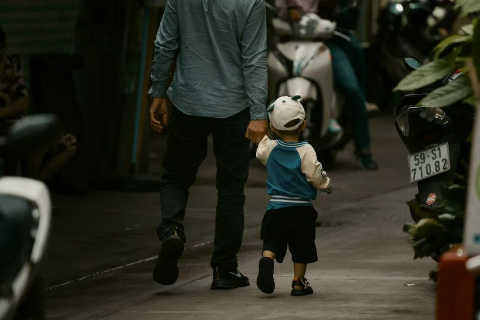 A father's hand guiding a child's hand — patient, present instruction over harsh authority