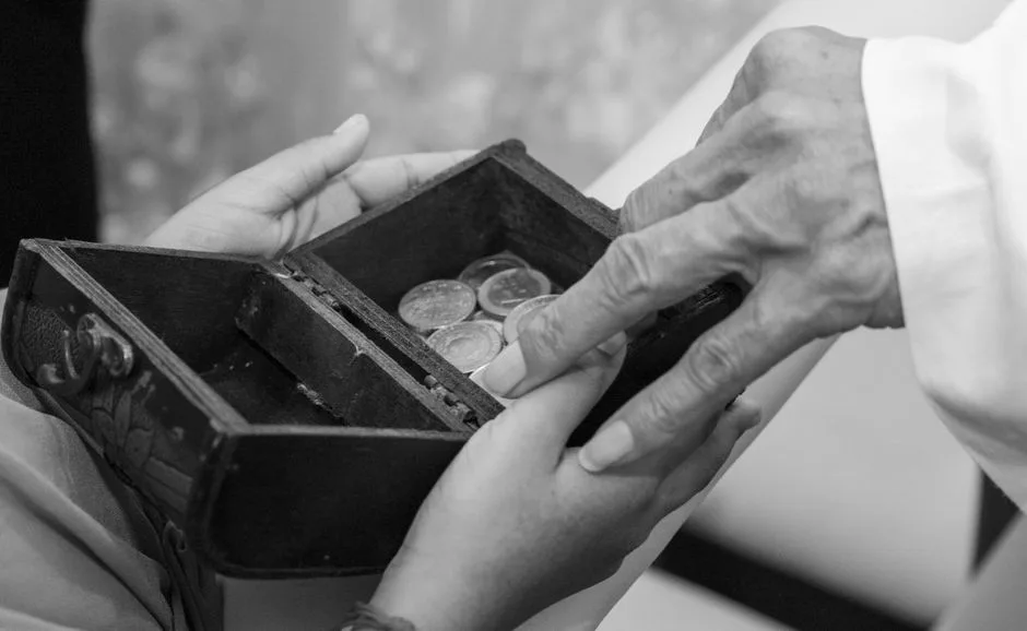 Open hands giving coins to another — generosity as a tool that loosens money's grip