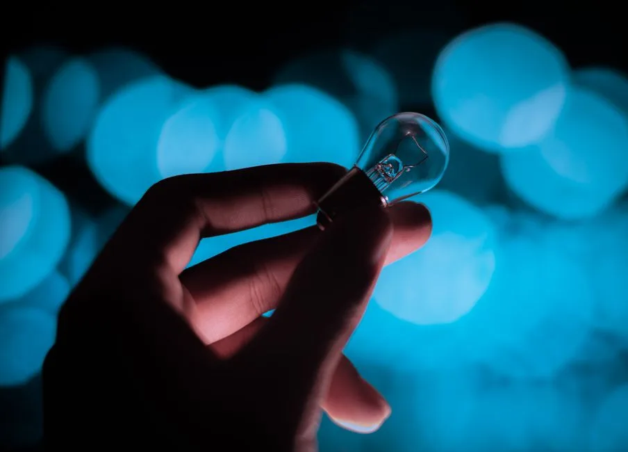 Hands gently holding a small light in darkness — the slow, real process of healing